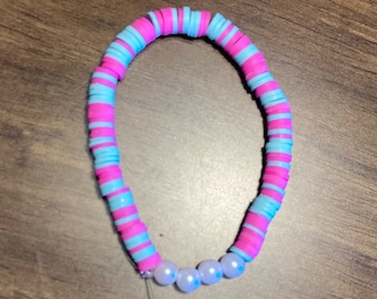 May include: A pink and blue beaded bracelet with white beads.