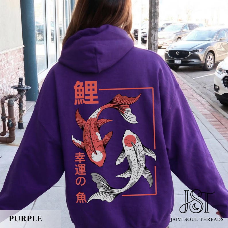 May include: A purple hoodie featuring a koi fish design. The back of the hoodie displays two koi fish in red and white, with Japanese text above and below the fish. The hoodie has a drawstring hood and long sleeves.