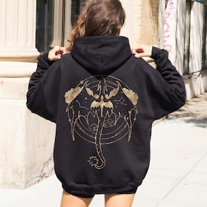 May include: Black hooded sweatshirt with a gold dragon graphic on the back. The dragon design includes wings, a tail, and celestial elements. The sweatshirt is a casual style.