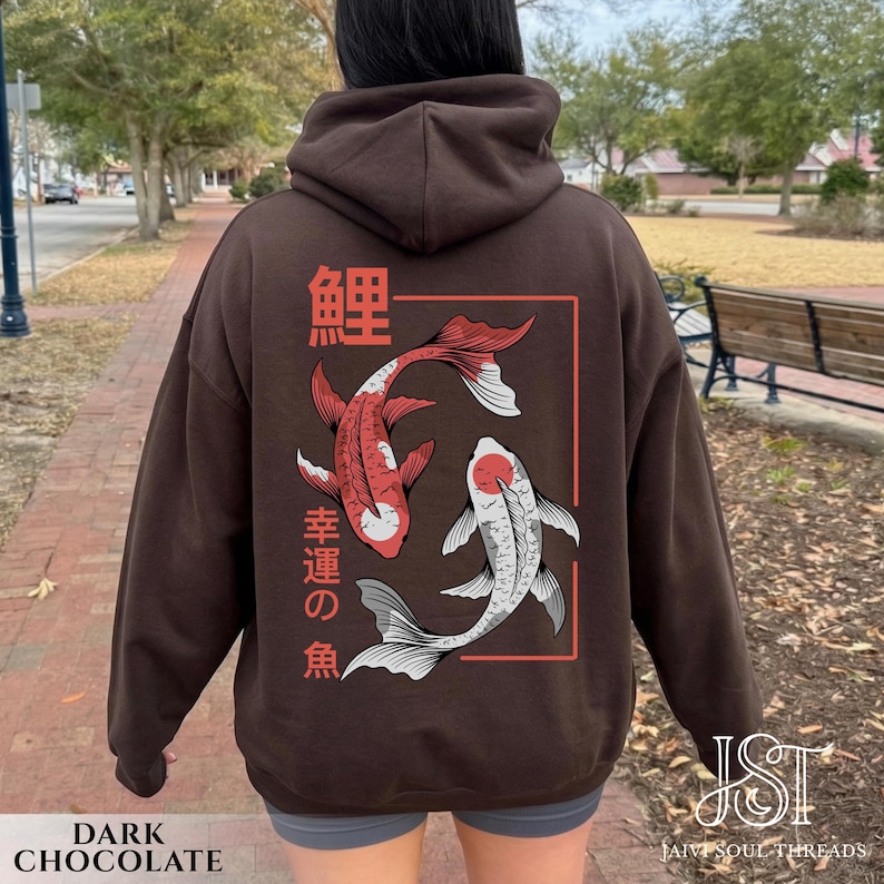 May include: Dark chocolate-colored hoodie featuring a red and white koi fish design with Japanese text. The design is framed in a red rectangle. The hoodie has a hood and a drawstring.