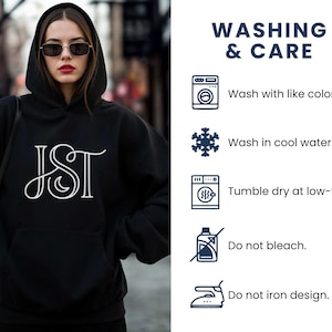 May include: A black hooded sweatshirt with a white JST design on the front. The image also includes washing instructions: wash with like colors, wash in cool water, tumble dry at low-temp, do not bleach, and do not iron design.