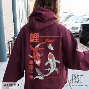 May include: Maroon hoodie featuring a Japanese koi fish design. The back of the hoodie displays two koi fish in red and white, with Japanese characters and a rectangular frame. The word "MAROON" is at the bottom left.