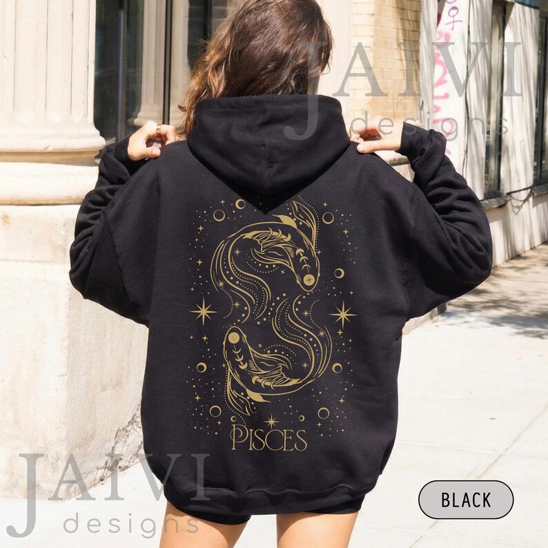 K&ouml;nnte beinhalten: Schwarzer Kapuzenpullover mit goldenem Fische-Sternzeichen-Design auf dem R&uuml;cken. Das Design zeigt zwei stilisierte Fische, Sterne und das Wort "PISCES". Der Hoodie hat eine Kapuze mit Kordelzug und lange &Auml;rmel.
