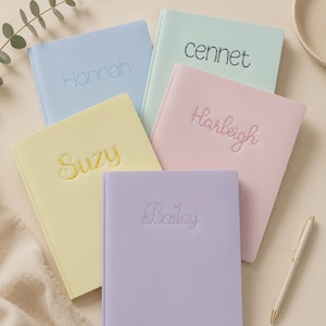 May include: Five hardcover journals in pastel colors including light blue, mint green, pale yellow, soft pink, and lavender. Each journal features a name embroidered on the front cover: Hannah, cennet, Suzy, Harleigh, and Bailey. A pen is included.