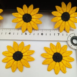 May include: Five yellow felt sunflower appliques with black centers. The appliques are approximately 2 inches in diameter.