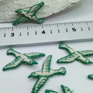 May include: A set of six green and white embroidered bird appliques. The birds are approximately 1 inch in length.