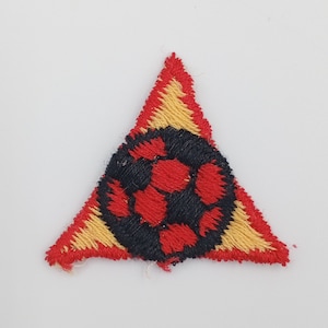 May include: A red, black, and yellow triangular patch with an embroidered soccer ball design.
