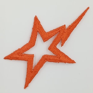 May include: Orange embroidered star-shaped patch with a jagged edge. The star is outlined with a second layer of stitching.