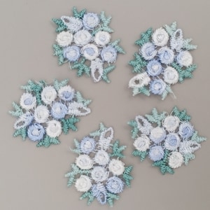 May include: Five blue and white embroidered flower appliques with green leaves. The appliques are perfect for adding a touch of vintage charm to any craft project.