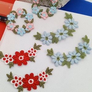 Puede incluir: Surtido de apliques florales bordados en varios colores, incluyendo rojo, azul y verde. Los apliques presentan diferentes diseños florales, incluyendo coronas y guirnaldas.
