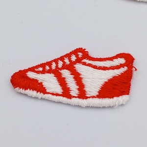May include: Red and white embroidered iron-on patch of a running shoe.