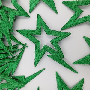 May include: A pile of green felt star-shaped patches. The stars have a jagged edge and are about 2 inches in size.