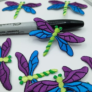 May include: A set of eight embroidered iron-on patches featuring colorful dragonflies with purple, blue, and green accents.