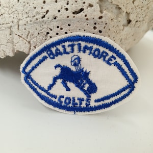 May include: Blue and white embroidered patch with the text "Baltimore Colts" and a blue silhouette of a horse and rider.