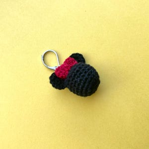 May include: A black crocheted keychain with a red bow and a silver loop.