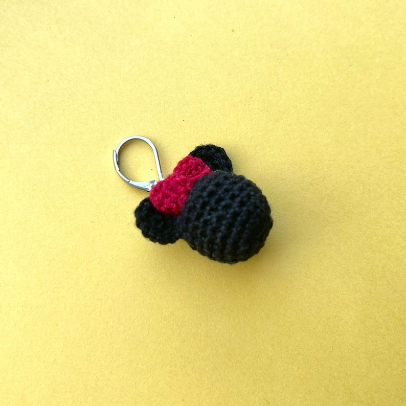 May include: A black crocheted keychain with a red bow and a silver loop.