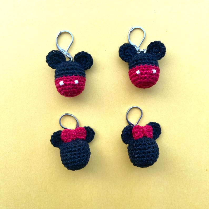 May include: Four crocheted keychains featuring Mickey Mouse and Minnie Mouse. The keychains are black with red accents and white eyes.