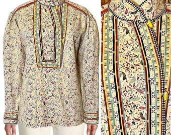 May include: A white cotton shirt with a colorful geometric pattern. The shirt has a high collar and long sleeves. The pattern is made up of red, green, yellow, and black stripes.