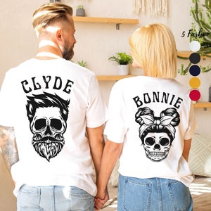 Könnte beinhalten: Ein Paar passende T-Shirts für ein Paar, jedes mit einem Totenkopf-Motiv. Das Shirt des Mannes sagt "CLYDE" und das Shirt der Frau sagt "BONNIE".
