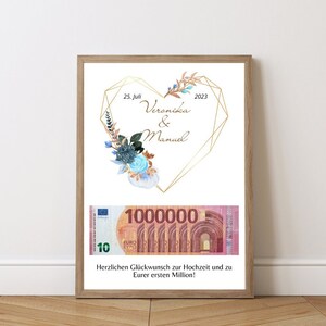 Puede incluir: Una impresión enmarcada con un diseño de corazón geométrico dorado y detalles florales. El corazón presenta el texto "25. Juli 2023 Veronika & Manuel". Un billete de euro de gran tamaño con el texto "1000000" se muestra debajo del corazón. El texto "Herzlichen Glückwunsch zur Hochzeit und zu Eurer ersten Million!" está en la parte inferior de la impresión.