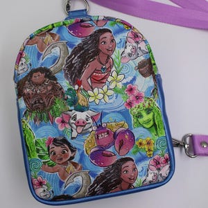 Puede incluir: Una mini mochila azul con tem&aacute;tica de Moana. La mochila presenta a Moana, Maui, Pua, Hei Hei y otros personajes de la pel&iacute;cula. La mochila tiene una correa morada.