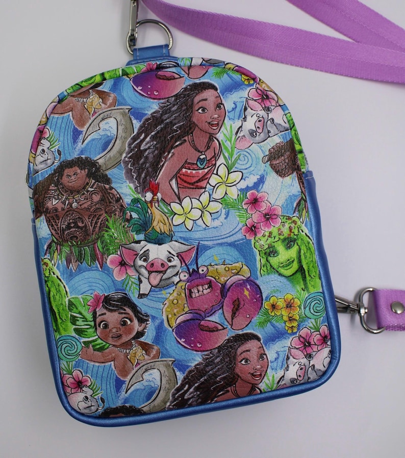 Puede incluir: Una mini mochila azul con tem&aacute;tica de Moana. La mochila presenta a Moana, Maui, Pua, Hei Hei y otros personajes de la pel&iacute;cula. La mochila tiene una correa morada.
