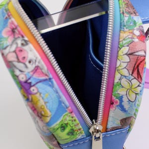 Puede incluir: Un peque&ntilde;o bolso azul en forma de coraz&oacute;n con cierre de cremallera. El bolso est&aacute; decorado con un estampado colorido de animales de dibujos animados y flores. El tirador de la cremallera es plateado.