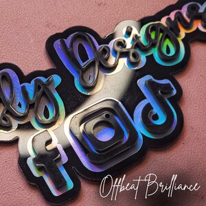 Puede incluir: Una pegatina negra e iridiscente con el texto "Only Designs" y los logotipos de Instagram, Facebook y TikTok. El texto "Offbeat Brilliance" est&aacute; escrito debajo de los logotipos.