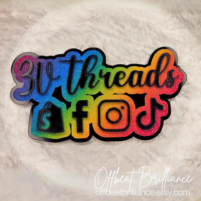 Puede incluir: Un letrero de acr&iacute;lico lleno de purpurina arco&iacute;ris con el texto "3lv threads" e iconos para Etsy, Facebook, Instagram y TikTok. El letrero est&aacute; hecho por Offbeat Brilliance y su sitio web es offbeatbrilliance.etsy.com.