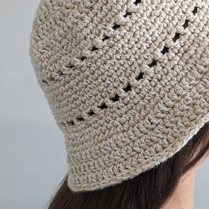 May include: A crocheted hat with a white and gold color scheme. The hat has a wide brim and a textured design.