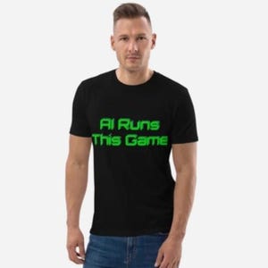 Op de afbeelding: Een zwart T-shirt met de tekst "AI Runs This Game" in groen.