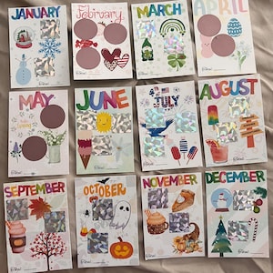 Può includere: Un set di dodici biglietti mensili gratta e vinci, ognuno con illustrazioni uniche e dettagli olografici. I biglietti presentano temi stagionali come pupazzi di neve, trifogli e zucche, con aree per rivelare contenuti nascosti. Ogni biglietto ha il nome del mese.