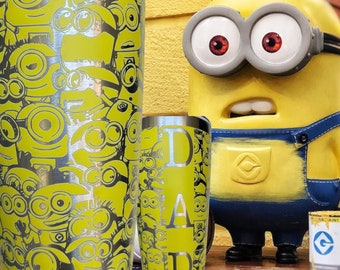 Puede incluir: Dos vasos de acero inoxidable con fondo amarillo y un patrón de Minions. El vaso más grande tiene un patrón completo de Minions, mientras que el vaso más pequeño tiene la palabra "DAD" en fuente plateada. Un personaje de Minion está en el fondo.