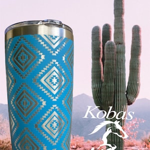 May include: A stainless steel tumbler with a light blue background and a silver geometric pattern. The tumbler has a silver rim and lid. The background features a desert landscape with a cactus and the text "Kobas Kreations".
