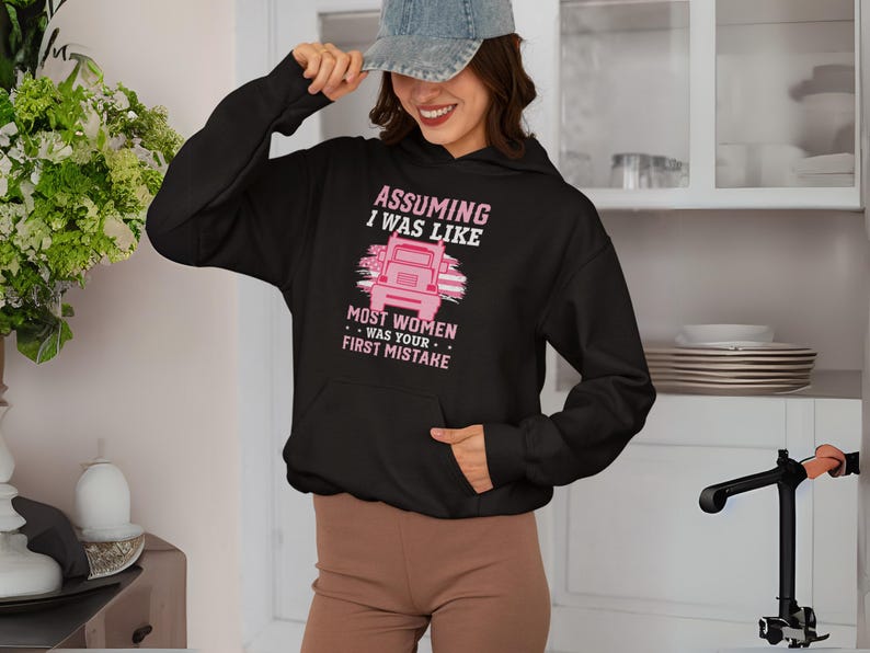 May include: Black hoodie with a pink graphic that says "Assuming I was like most women was your first mistake". The graphic also features a pink semi-truck.