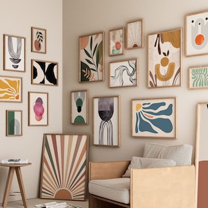 May include: A gallery wall with a variety of abstract art prints in different colors and shapes. The prints are framed in natural wood and arranged in a modern and eclectic style.