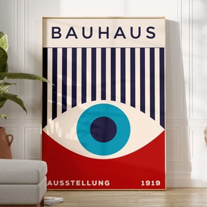 Puede incluir: Un póster de Bauhaus con un gráfico de ojo rojo, blanco y azul. El póster tiene el texto "BAUHAUS" en letras negras en la parte superior y "AUSSTELLUNG 1919" en letras negras en la parte inferior.