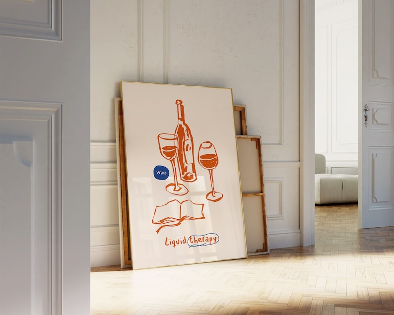 May include: A white framed print with a hand-drawn illustration of a wine bottle and two glasses. The text "Wine" is in a blue circle and the text "Liquid Therapy" is below the illustration.