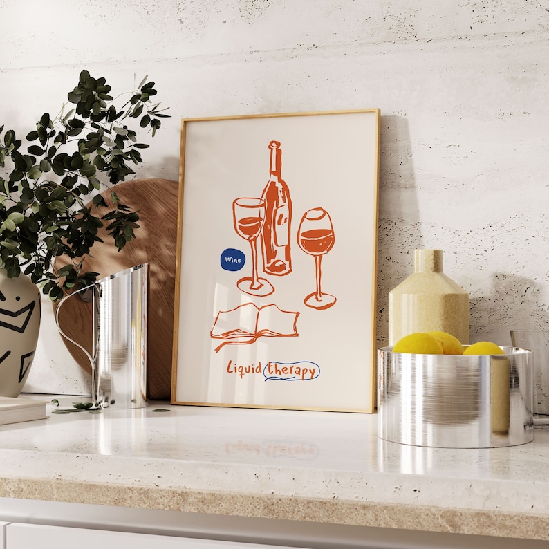May include: A framed print with a red and orange illustration of a wine bottle and two glasses. The text "Wine" and "Liquid Therapy" are included in the illustration.