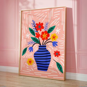 Puede incluir: Una impresi&oacute;n floral colorida con un jarr&oacute;n de rayas azules y blancas. Las flores son rojas, amarillas y naranjas con hojas verdes. El fondo es rosa claro con l&iacute;neas blancas.