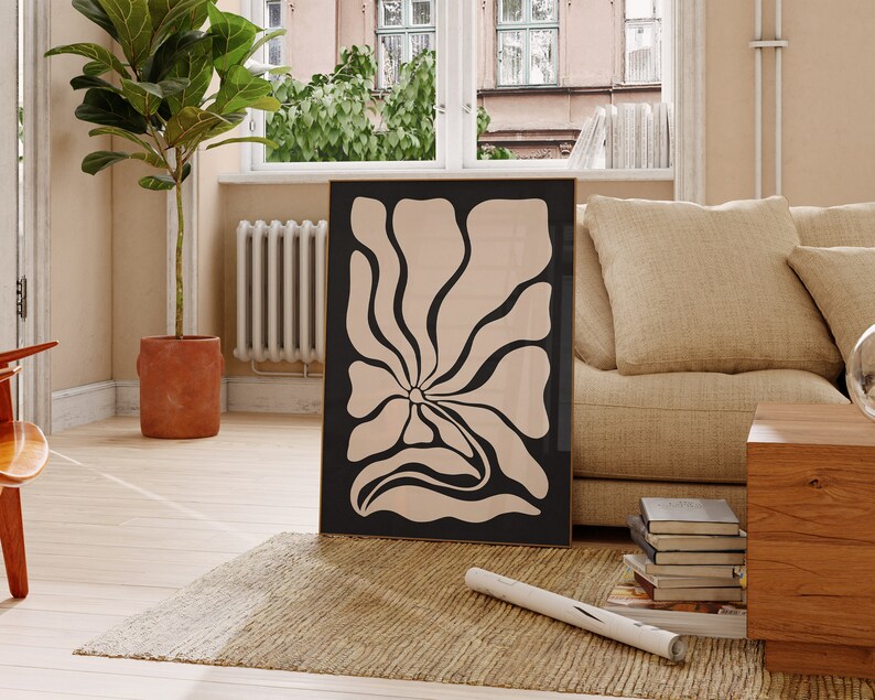 May include: A black framed print of a large, abstract flower with a beige background. The flower has a stylized, organic shape with rounded edges.
