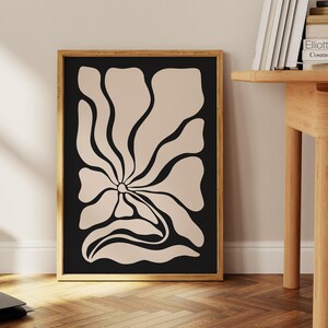 May include: A framed print of a stylized flower with a beige outline on a black background.