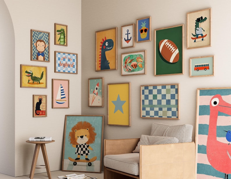 May include: A gallery wall of framed art prints featuring whimsical illustrations. The collection includes a dinosaur, a lion on a skateboard, a football, a pineapple with sunglasses, and a rocket ship. The color palette includes blues, yellows, and greens.
