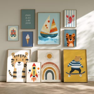 May include: A collection of framed art prints featuring whimsical illustrations. The prints include a sailboat, tiger, bear on a skateboard, rocket, rainbow, and a lobster. One print reads "COOL KIDS LIVE HERE". The artwork is in a colorful, playful style.