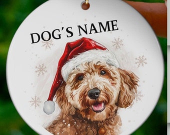 May include: A white ceramic Christmas ornament with a watercolor illustration of a dog wearing a Santa hat. The ornament is personalized with the text "DOG'S NAME".