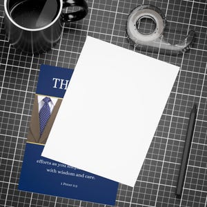 以下が含まれることがあります： 「TH」と「efforts as you shep with wisdom and care. 1 Peter 5:2」というテキストが書かれた青と金のカード。カードには、青いネクタイをつけた茶色のスーツが描かれている。