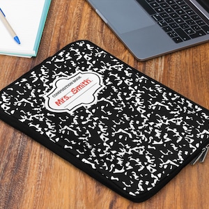 May include: Black and white composition book laptop sleeve with a red label that says "COMPOSITION BOOK MRS. SMITH".