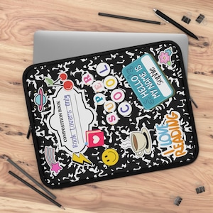 Puede incluir: Funda para portátil negra y blanca con diseño de papel de cuaderno. La funda presenta varias pegatinas de colores con texto como "COOL" e "I LOVE READING".