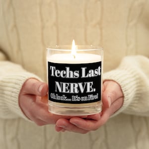 May include: A clear glass candle with a black label that reads "Techs Last NERVE. Oh look... It's on Fire!"