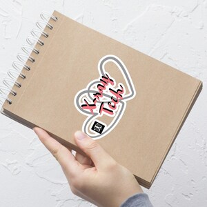 May include: A gray and white heart-shaped sticker with the text "Xray Tech" in pink lettering. A small black and white image of a pair of lungs is inside the heart.